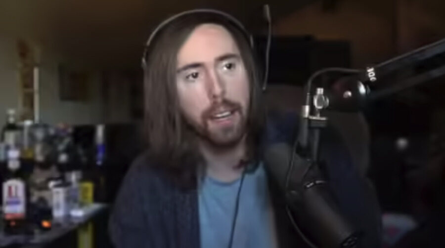 Asmongold on stream at his microphone in a cluttered room