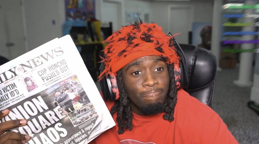 Kai Cenat on stream, holding up a newspaper to the camera