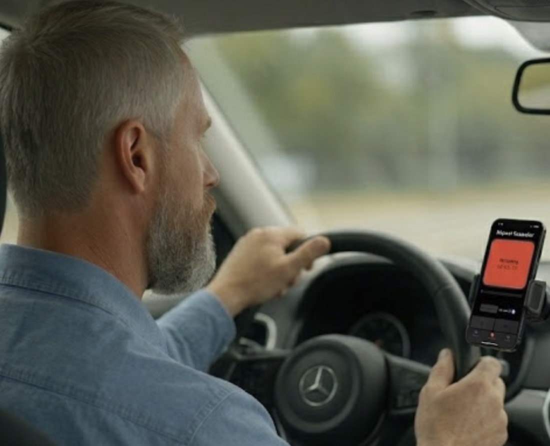 A driver using Repeat Recorder hands-free in a phone mount, the app recording on its red screen, with both hands free for the wheel